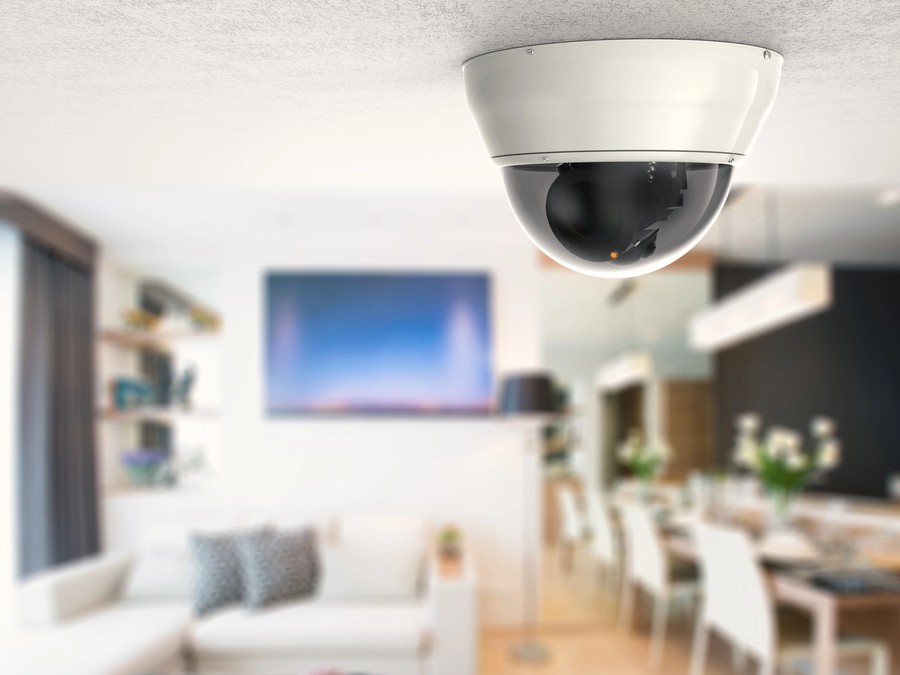 Ceiling-mounted dome security camera installed in a modern luxury living room. 