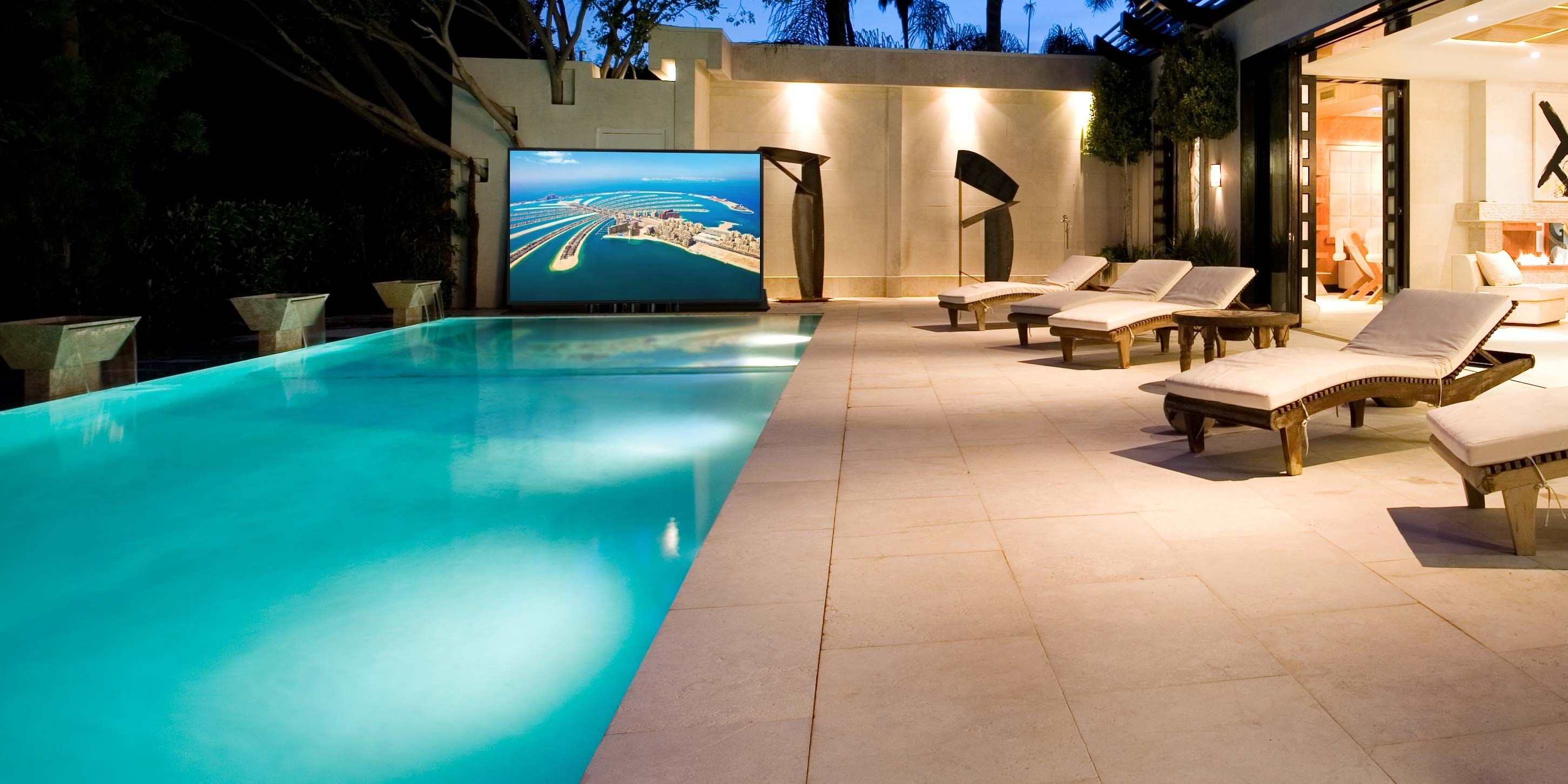outdoor lounge area with a pool and motorized TV lift by Nexus 21